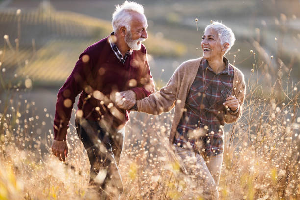 istock Cheerful mature couple talking while walking through tall grass in nature. 1206781838