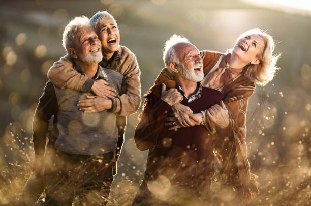 istock Cheerful mature couples having fun while piggybacking in autumn day. 1206783150