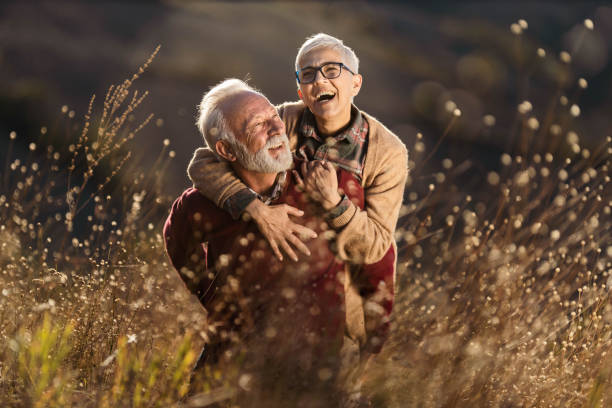 istock Playful mature couple having fun while piggybacking in tall grass. 1206783538