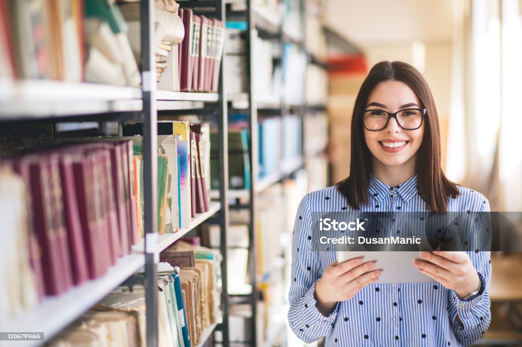 Portrait of college student studying in the library using tablet PC Librarian Stock Photo