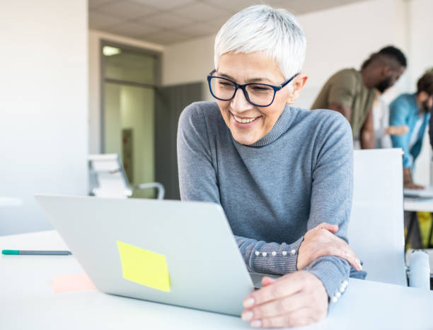 istock A senior employee looking at a lap top in an office. 1206792096