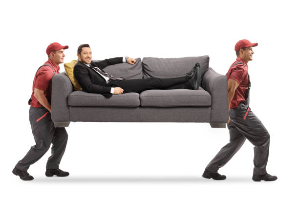istock Movers carrying a sofa with a man in a suit relaxing on the sofa 1206794540