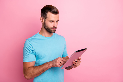 Photo of white serious confident man typing on his tablet electronic device touching, screen looking thoughtfully isolated pastel color background