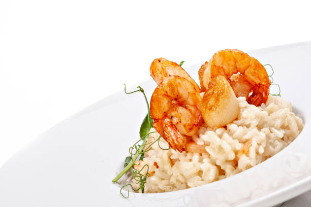 Seafood risotto in plate decorated with microgreens sprig. Studio shot. Isolated on white background.