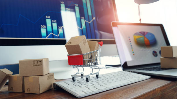 オンラインショッピング、テーブル上のボックスとラップトップキーボードのトロリーのボックスと画面の背景上のビジネスグラフの成長、電子商取引。 - eコマース ストックフォトと画像