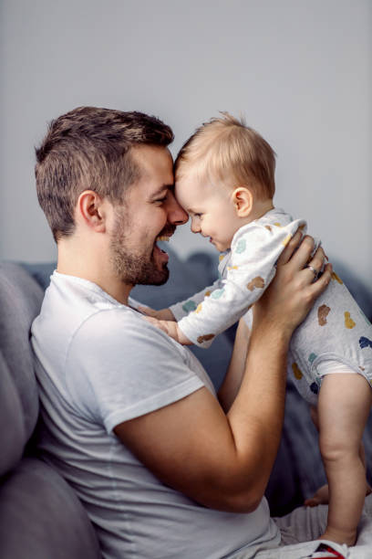 Young attractive caring father holding his beloved little son, talking to him and having teaching him standing. Young attractive caring father holding his beloved little son, talking to him and having teaching him standing. father and baby stock pictures, royalty-free photos & images