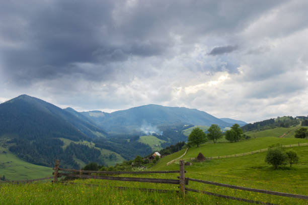 istock Carpathian slopes with fenced hayfields on a foreground 1206799105