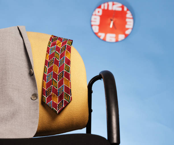 Suit jacket and necktie on chair as clock shows late hour