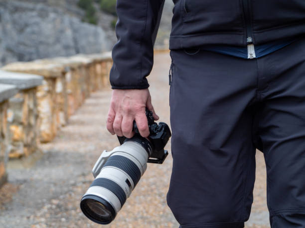 istock Hand of a man holding a camera outdoors in the middle of a path 1206801908