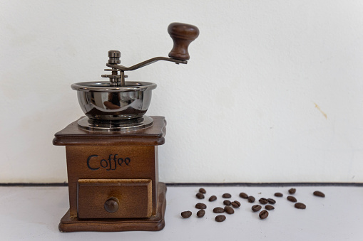 Manual wooden coffee grinder for grinding coffee beans. White background.
