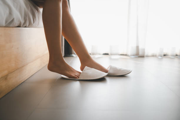 woman legs with slippers closeup woman legs with slippers sitting on bed slipper stock pictures, royalty-free photos & images