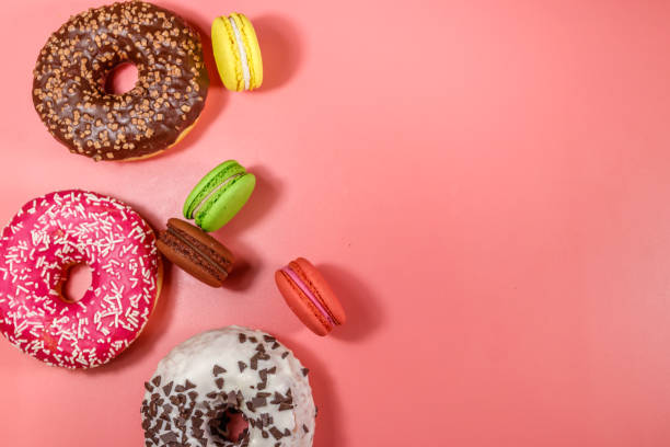istock Tasty donuts and macaroons on pink background. Top view, copy space 1206803381