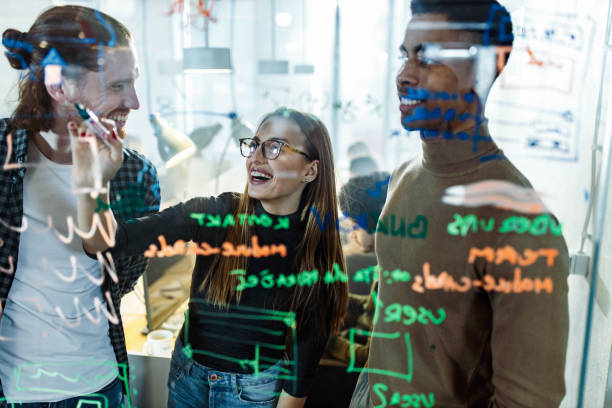 istock Team of happy programmers analyzing plans on glass wall in the office. 1206803583