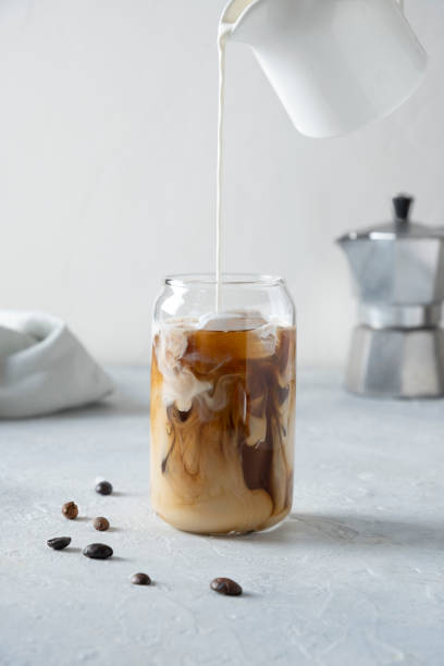 café au lait glacé dans le verre avec le lait versant. fermez-vous vers le haut. verticale. - milk shake coffee latté cold photos et images de collection