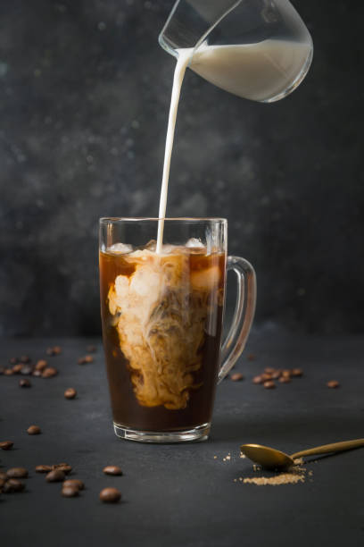 iced latte coffee in cup glass with pouring milk on black - pouring coffee liquid coffee bean imagens e fotografias de stock