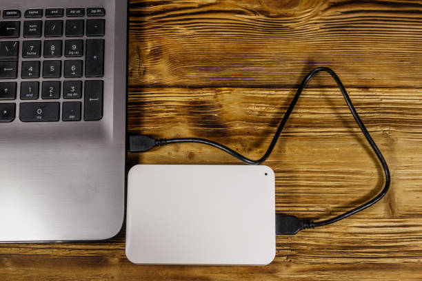 istock External HDD connected to laptop computer on a wooden desk. Top view. Concept of data storage 1206804914