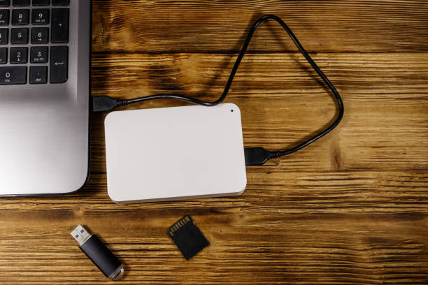 istock External HDD connected to laptop computer, SD memory card and USB flash drive on a wooden desk. Top view. Concept of data storage 1206804922