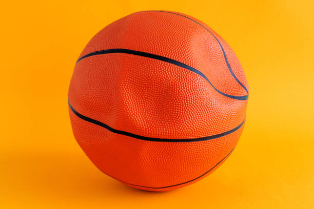 Deflated basketball ball on yellow background, close up selective focus