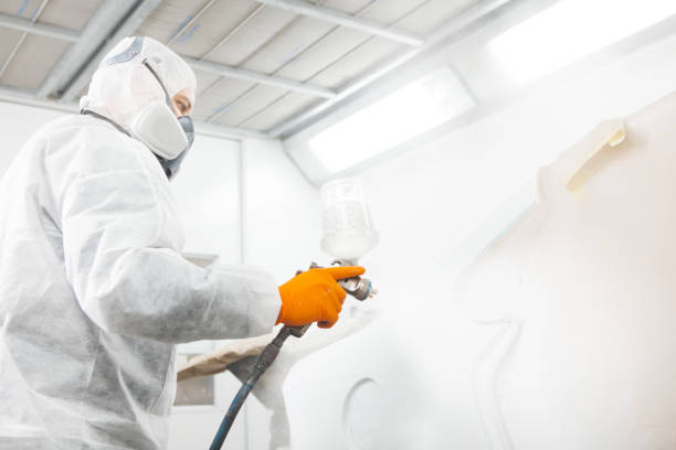 istock Worker paints auto elements with spray gun. White car in a paint chamber during repair work. 1206807581