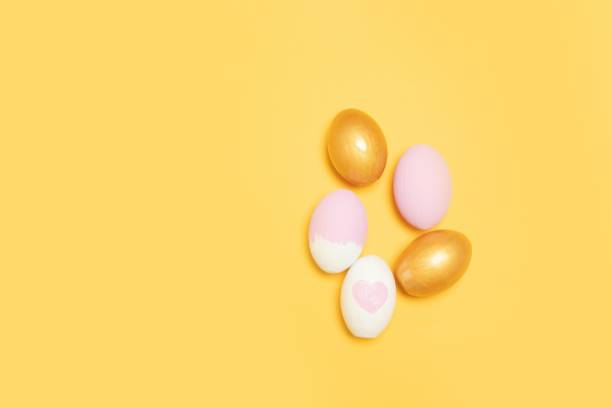 istock Top view of gold and pink easter eggs on yellow background 1206808365