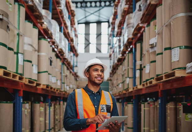 istock Handsome warehouse worker uses digital tablet for checking stock, on the shelves standing cardboard boxes 1206808526