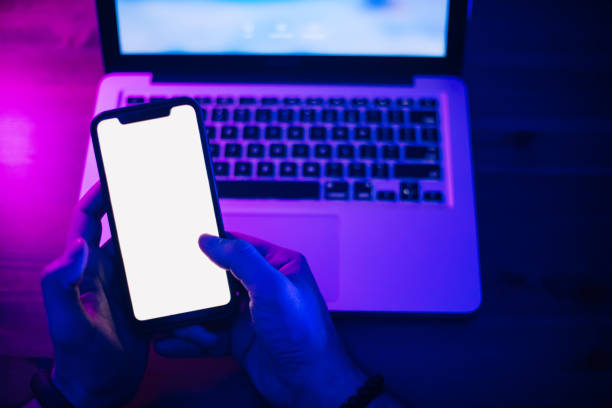 istock Top view of using smartphone in purple neon light 1206810627