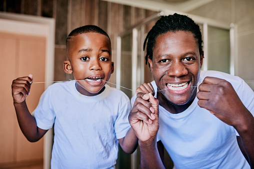 Cropped shot of a young man and his son flossing their teeth in the bathroom at home