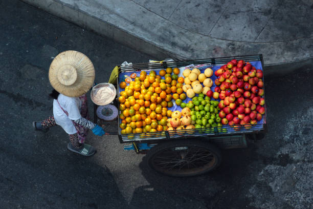 Street fruit vendor pushes her wheelbarrow in Phaya Thai district of Bangkok, Thailand stock photo