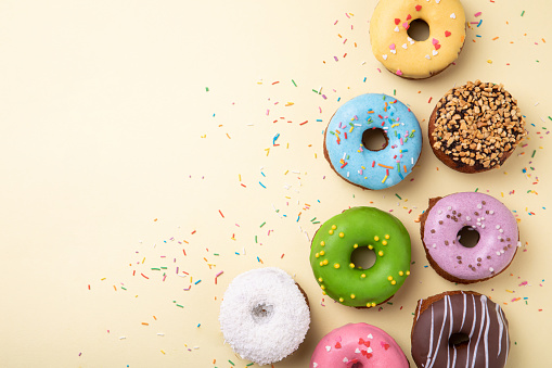 Top view of set of donuts on yellow background. Flat lay, copy space.