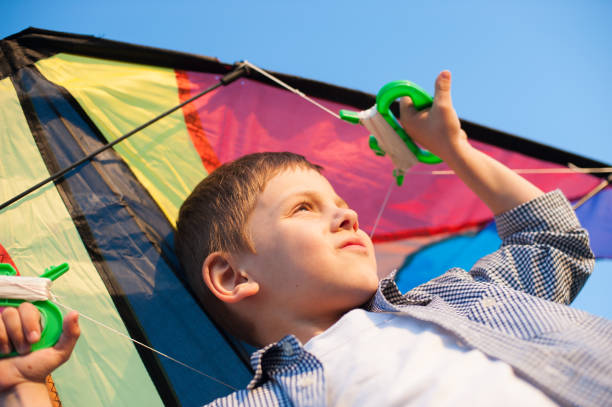 istock beautiful kid holds kite over his head against blue sky 1206816512