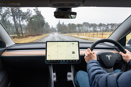 Edinburgh, Scotland - A view from the rear of a Tesla Model 3, driving in wet conditions on a country road south of Edinburgh.