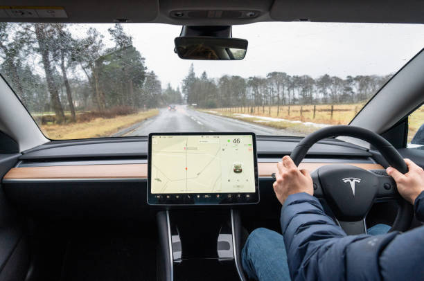 Tesla Model 3 journey Edinburgh, Scotland - A view from the rear of a Tesla Model 3, driving in wet conditions on a country road south of Edinburgh. tesla model 3 stock pictures, royalty-free photos & images