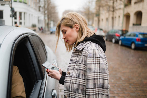 Tourist Woman talking to an uber driver Woman talking to an uber taxi driver in bad weather friedrichshain photos stock pictures, royalty-free photos & images