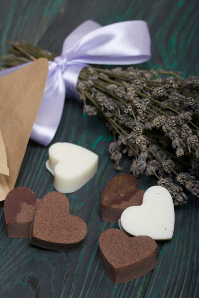 istock An open white paper bag on brushed pine boards. Chocolate hearts are scattered from it. From white and black chocolate. Near a bouquet of lavender. 1206820148