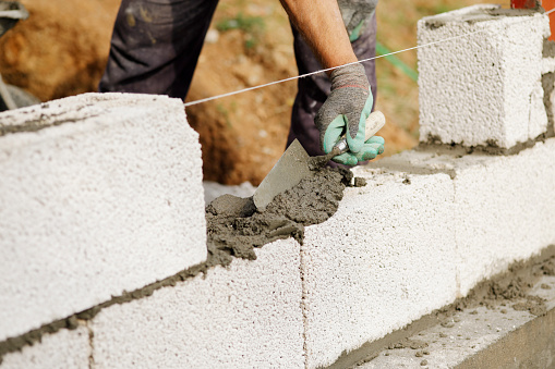 Close-up of construction worker builds brick wall