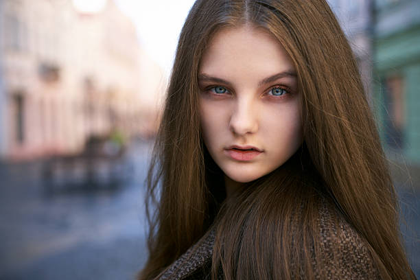 Portrait of a young woman, wearing casual clothes, with long hair in urban background