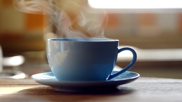 Hot coffee cup steaming on table