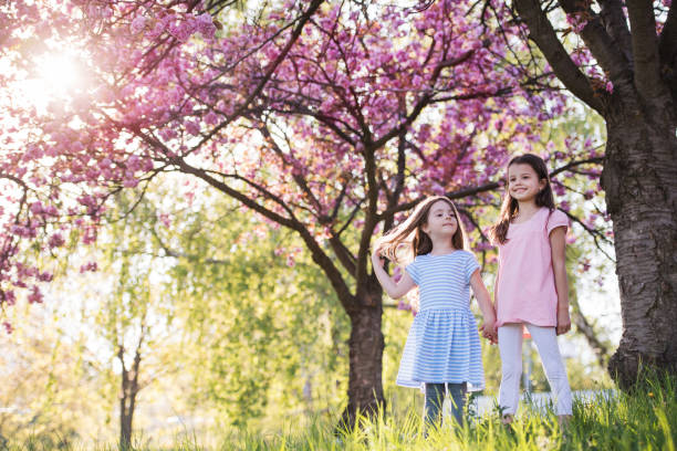 istock Two small girls standing outside in spring nature. Copy space. 1206823753