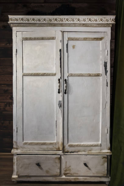 istock Old painted white cabinet with decorative borders and metal door knobs on dark background. Vintage wooden furniture. 1206823953