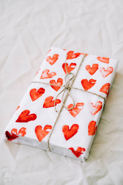 istock a gift wrapped in homemade wrapping paper with red hearts tied with jute thread for Valentine's day on a white table 1206830404