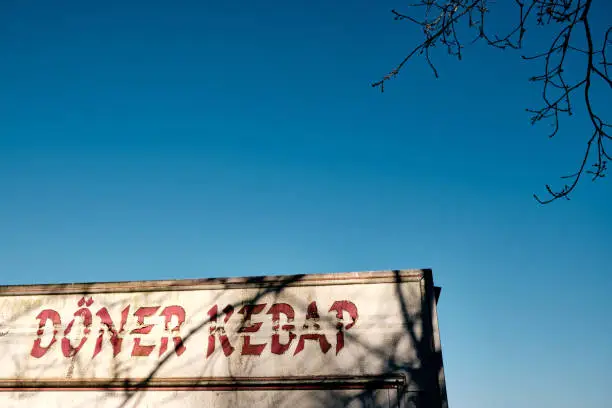 Photo of Close - up of the words Döner Kebap (english: doner kebab ) on an old trailer against blue sky