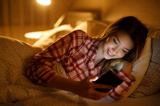 istock Beautiful young woman using mobile phone in bed at night 1206835808