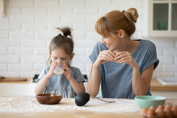 happy mom and little daughter enjoy weekend in home kitchen - milk child drinking little girls imagens e fotografias de stock