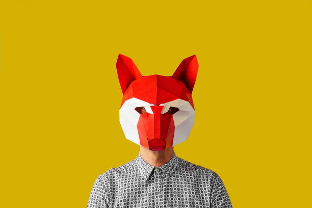 young man with a red fox mask young caucasian man wearing a red and white fox mask on a yellow background with some blank space around him wolf snout pictures stock pictures, royalty-free photos & images