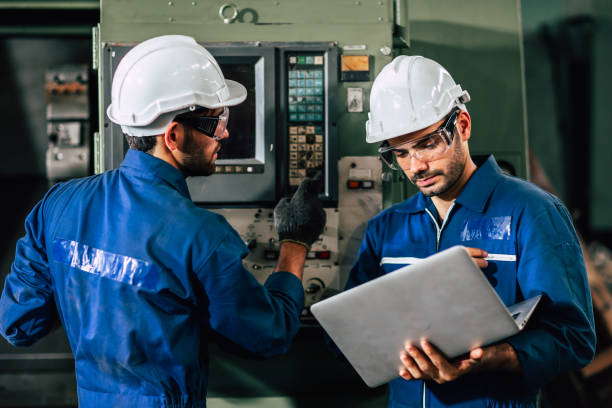 le travailleur d’équipe d’ingénieur d’industrie actionnent la machine lourde de commande avec l’ordinateur portable pour aider à analyser le problème d’opération. - electrical system photos et images de collection