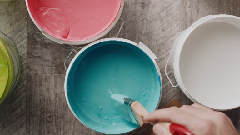 Man's hand taking paint from the bucket with paintbrush