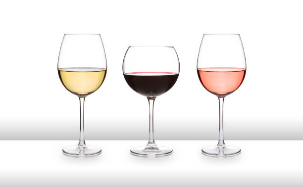 três taças de vinho, branco, vermelho e rosa, em um bar branco como superfície, com um fundo branco e lata graduada - white wine wine white glass - fotografias e filmes do acervo