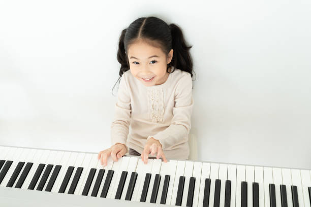 glückliche asiatische vorschulkind spielen klavier im haus - music learning child pianist stock-fotos und bilder