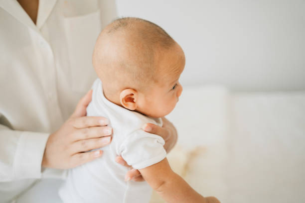 mutter klopft auf den rücken des asiatischen babys - baby newborn chinese ethnicity asian ethnicity stock-fotos und bilder