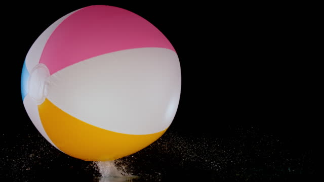 SLO MO LD Inflatable beach ball bouncing on black surface